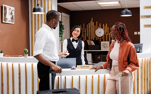 Receptionist giving room key card to couple arriving at hotel