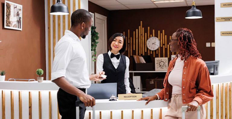 Receptionist giving room key card to couple arriving at hotel