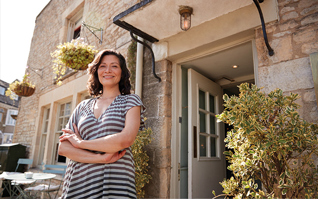 Female guesthouse owner standing outside her business