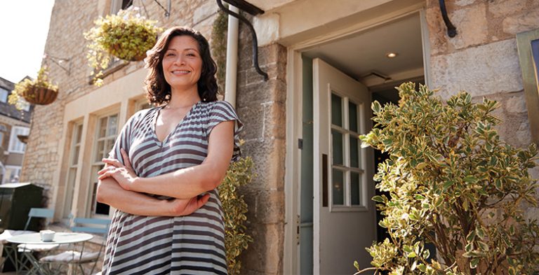 Female guesthouse owner standing outside her business