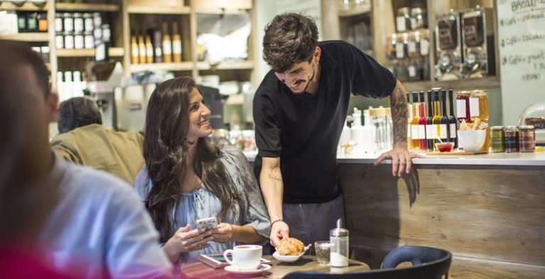 Barista serving a young lady in a cafe