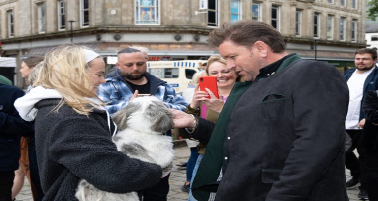 A person holding a dog whilst James Martin strokes it