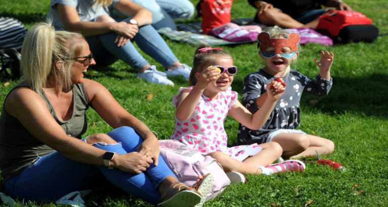 an adult and two children sat on grass