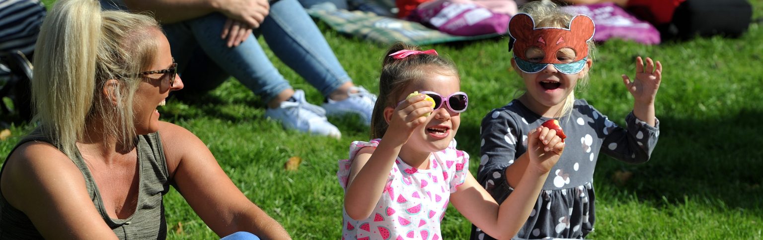 an adult and two children sat on grass